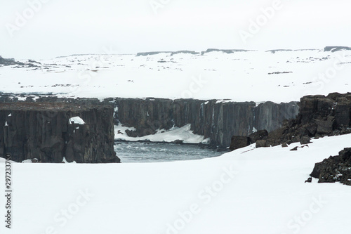 Selfoss waterfall (part of Jökulsá á Fjöllum river in the north of Iceland originating from Vatnajokull glacier) in winter, pictured with snow icicles, snow patterns and spray over the stream 