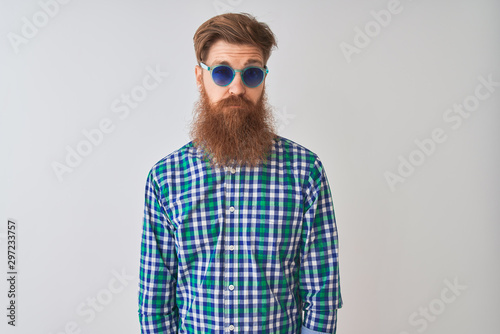 Young redhead irish man wearing casual shirt and sunglasses over isolated white background skeptic and nervous, frowning upset because of problem. Negative person.
