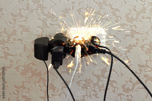 Overloaded socket, spark. Danger of electric shock, fire. Wire, plug, fire. photo