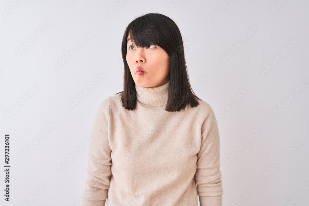 Young beautiful chinese woman wearing turtleneck sweater over isolated white background making fish face with lips, crazy and comical gesture. Funny expression. Young beautiful chinese woman wearing turtleneck sweater over isolated white background making fish face with lips, crazy and comical gesture. Funny expression.