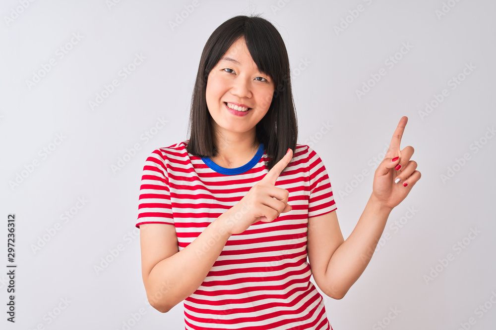 Young beautiful chinese woman wearing red striped t-shirt over isolated white background smiling and looking at the camera pointing with two hands and fingers to the side. Young beautiful chinese woman wearing red striped t-shirt over isolated white background smiling and looking at the camera pointing with two hands and fingers to the side.
