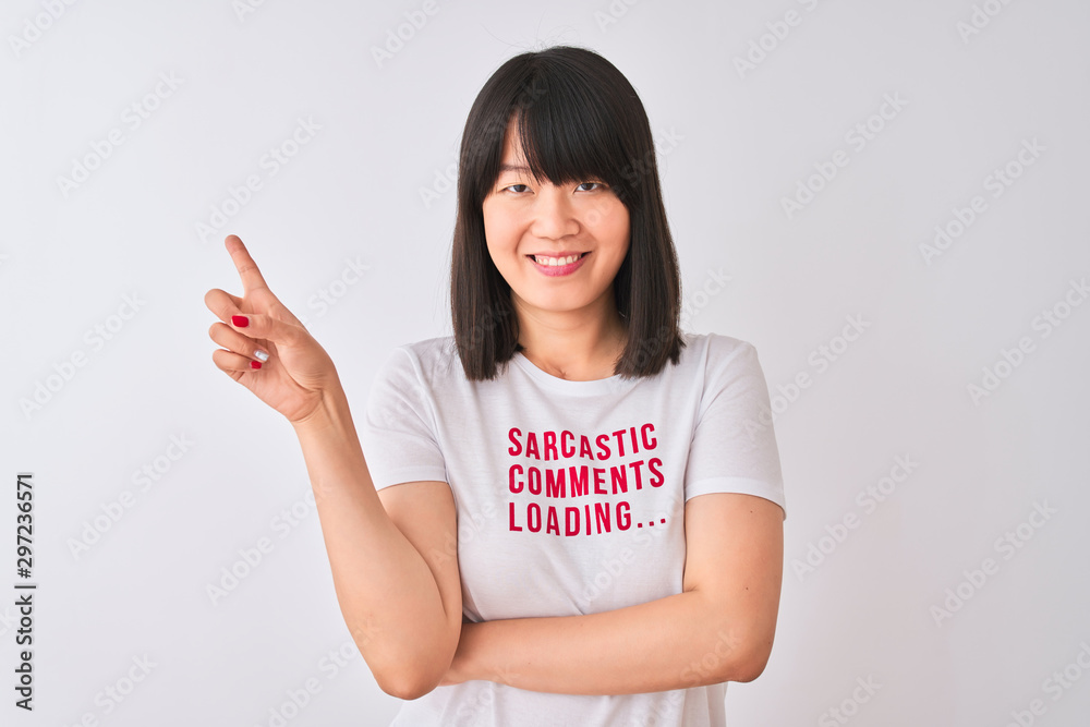 Young beautiful Chinese woman wearing fanny t-shirt over isolated white background very happy pointing with hand and finger to the side Young beautiful Chinese woman wearing fanny t-shirt over isolated white background very happy pointing with hand and finger to the side