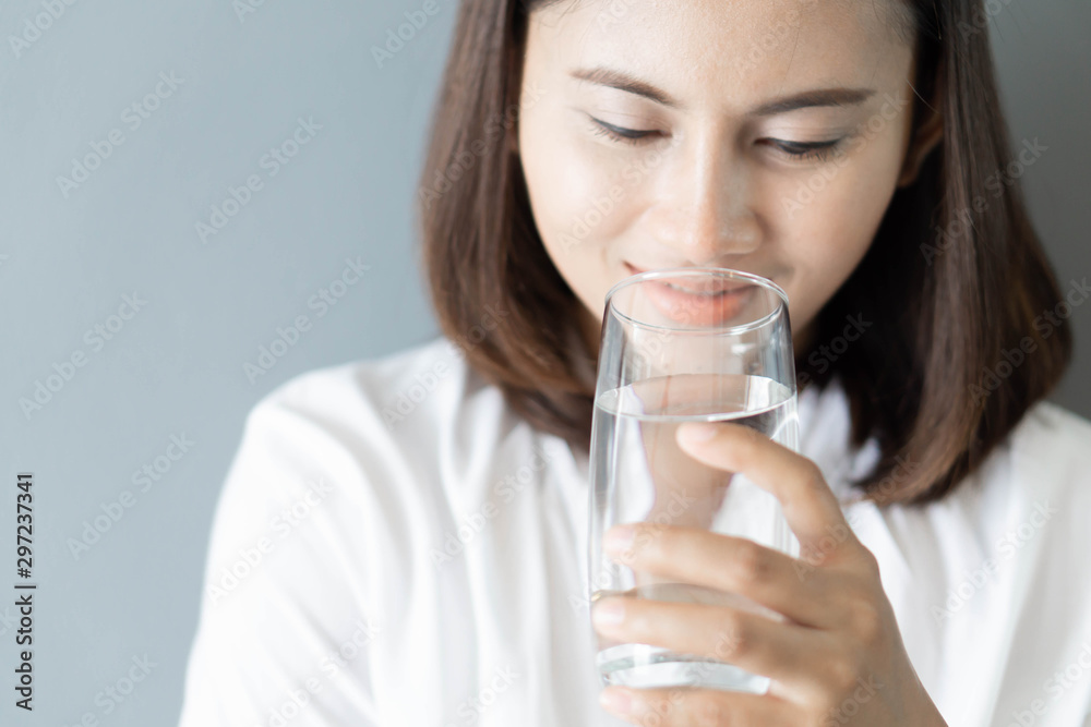 Close up woman drinking pure water from glass with light in the morning, Selective focus Close up woman drinking pure water from glass with light in the morning, Selective focus
