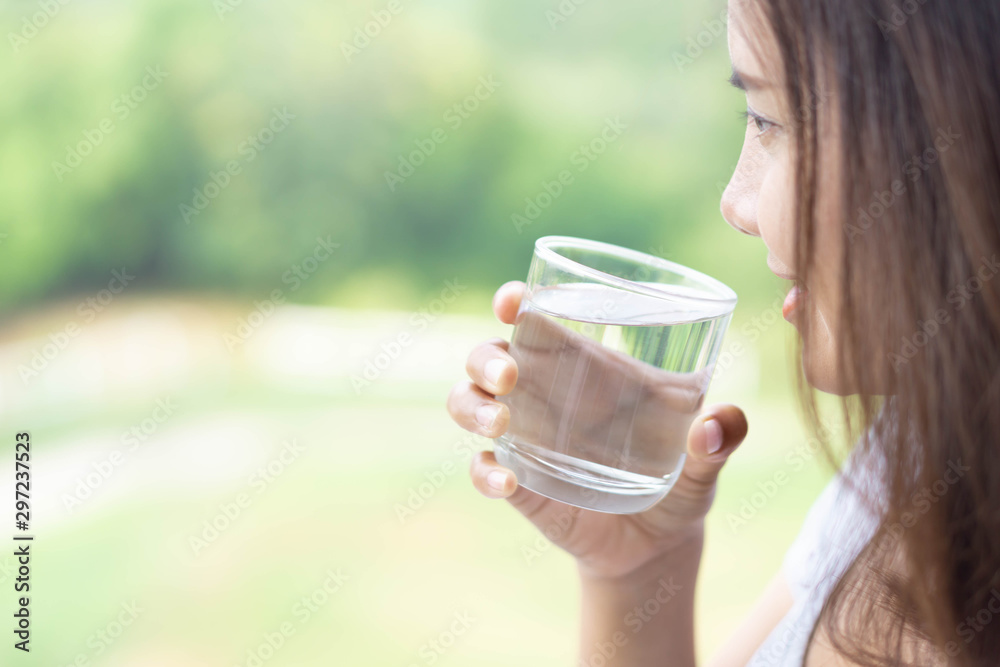 Close up woman drinking pure water from glass with light in the morning, Selective focus Close up woman drinking pure water from glass with light in the morning, Selective focus