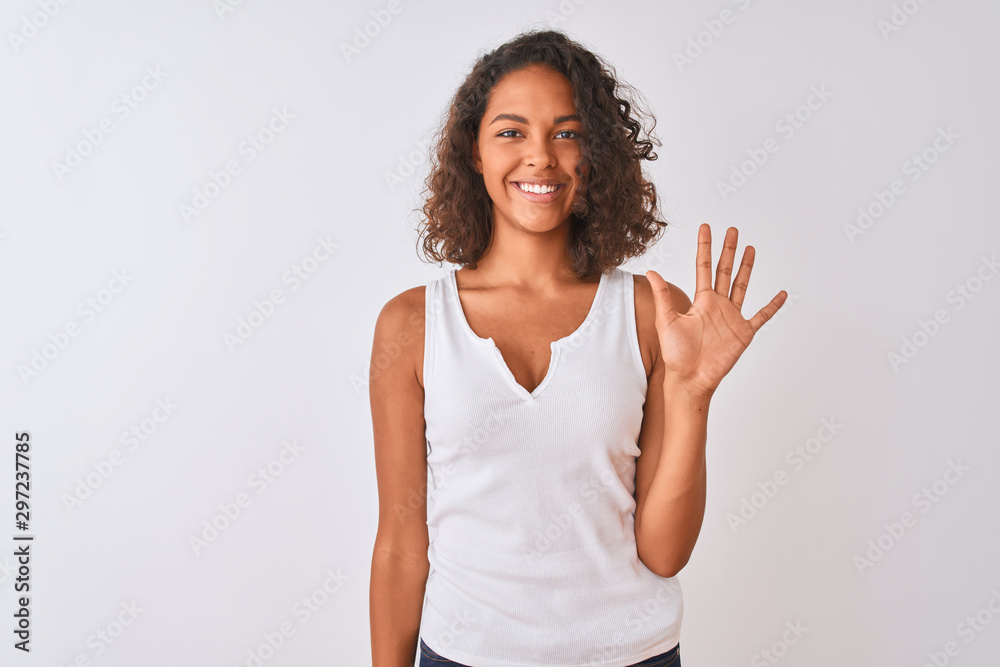 Young brazilian woman wearing casual t-shirt standing over isolated white background showing and pointing up with fingers number five while smiling confident and happy. Young brazilian woman wearing casual t-shirt standing over isolated white background showing and pointing up with fingers number five while smiling confident and happy.