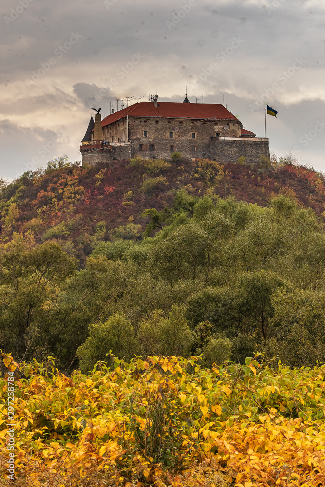 Palanok Castle or Mukachevo Castle. Ukraine. Beautiful landscape with a medieval Mukachevo castle on a mountain among colorful fall foliage on a cloudy day.