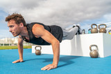 Decline push Up fitness man doing strength training exercise pushup at outdoor gym with feet elevated.
