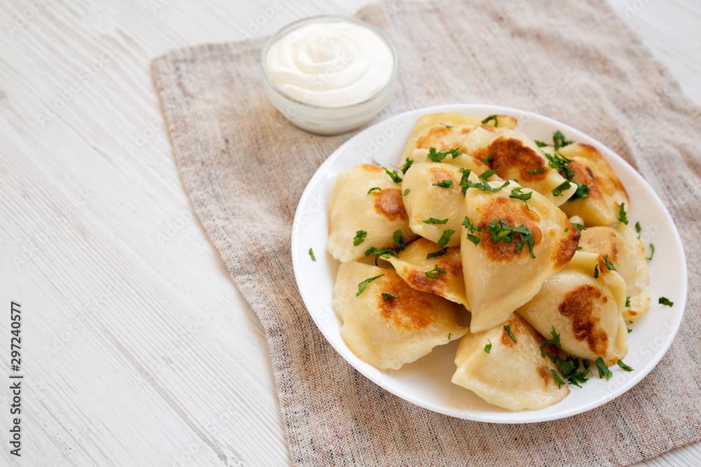Homemade traditional polish fried potato pierogies on a white plate, low angle view. Copy space. Homemade traditional polish fried potato pierogies on a white plate, low angle view. Copy space.