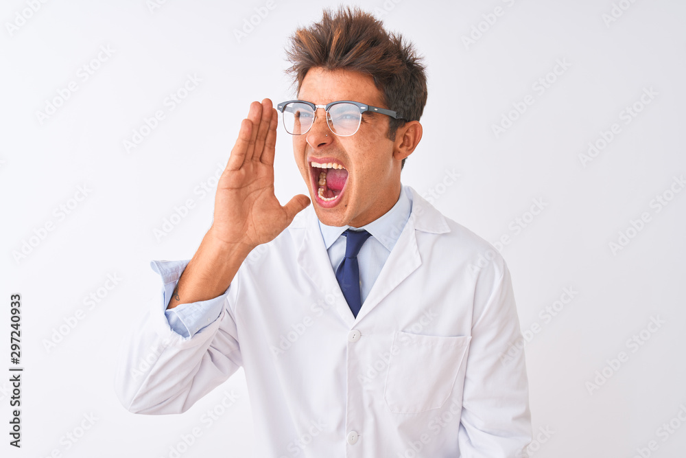 Young handsome sciencist man wearing glasses and coat over isolated white background shouting and screaming loud to side with hand on mouth. Communication concept. Young handsome sciencist man wearing glasses and coat over isolated white background shouting and screaming loud to side with hand on mouth. Communication concept.