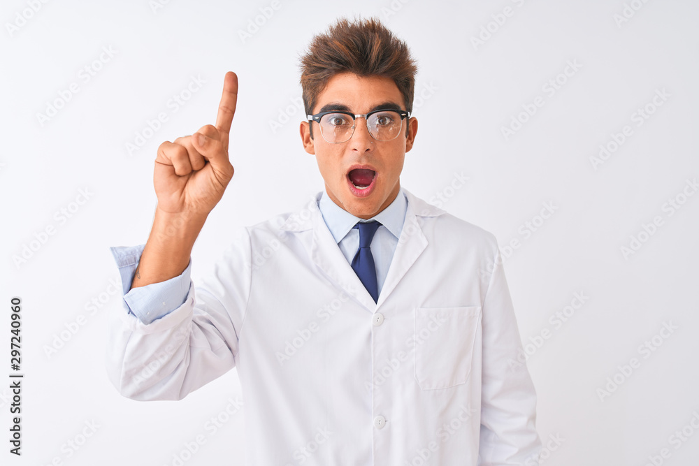 Young handsome sciencist man wearing glasses and coat over isolated white background pointing finger up with successful idea. Exited and happy. Number one. Young handsome sciencist man wearing glasses and coat over isolated white background pointing finger up with successful idea. Exited and happy. Number one.