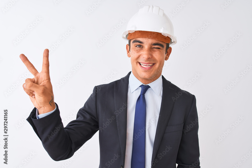 Young handsome architect man wearing suit and helmet over isolated white background smiling with happy face winking at the camera doing victory sign. Number two.