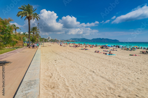 People relax at seaside sand beach in Cala Millor on Mallorca island, Spain