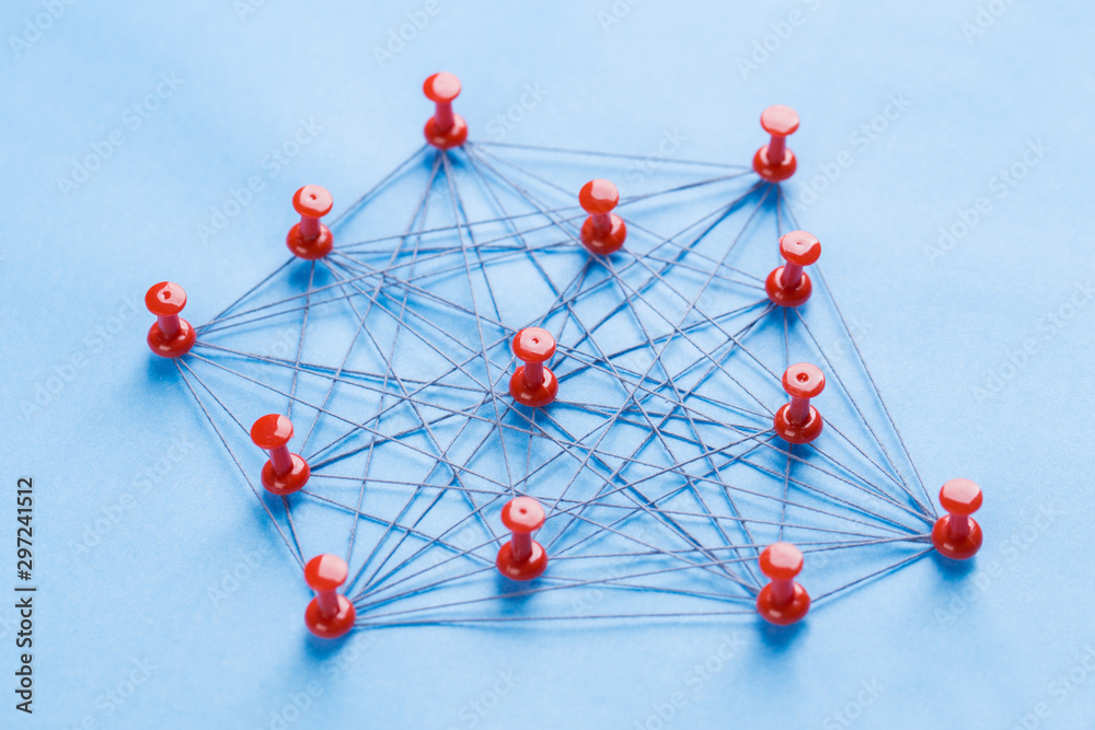network with red pins and string, An arrangement of colorful pins linked together with string on a blue background suggesting a network of connections. network with red pins and string, An arrangement of colorful pins linked together with string on a blue background suggesting a network of connections.
