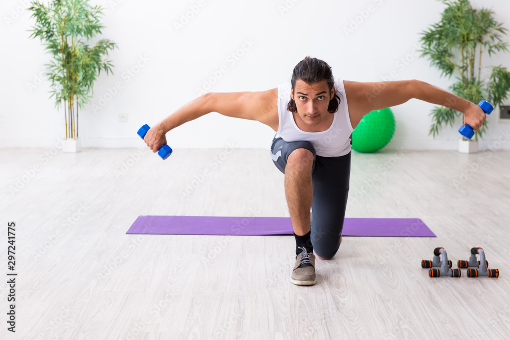 Fototapeta premium Young handsome man doing sport exercises indoors