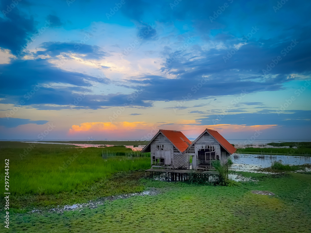 Old twin houses in the grass fields with beautiful clouds and sky during sunset time. Old twin houses in the grass fields with beautiful clouds and sky during sunset time.
