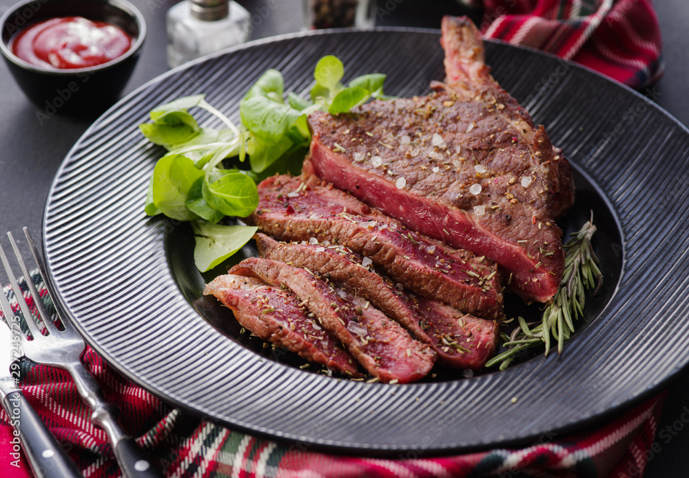 Steak on the bone. Rib eye. Tomahawk steak on the black plate with rosemary. Roasting - Rare. Entrecote Steak on the bone. Rib eye. Tomahawk steak on the black plate with rosemary. Roasting - Rare. Entrecote