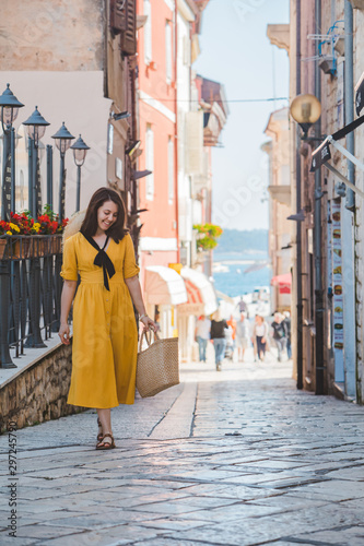 young pretty woman in yellow dress walking by small porec city streets sea on background © phpetrunina14