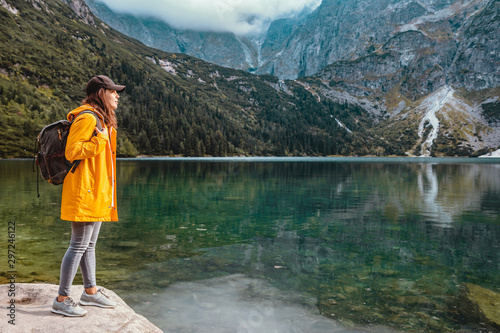 woman in yellow raincoat at lake beach in tatra national park