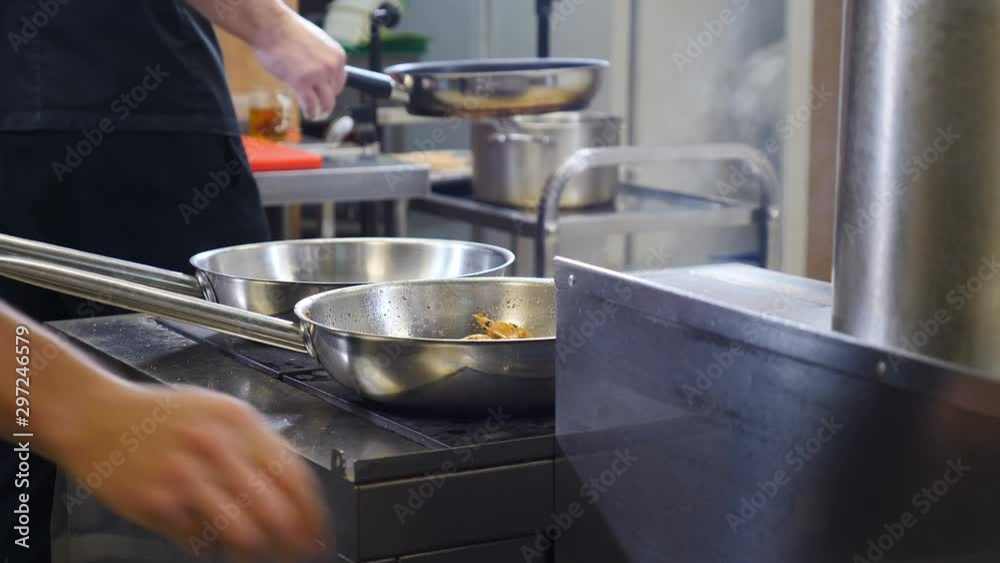 Restaurant kitchen rush. Closeup. Teamwork of kitchen staff preparing food. Chef tossing and throwing frying pan with shrimps on stove. Shot in 4k Restaurant kitchen rush. Closeup. Teamwork of kitchen staff preparing food. Chef tossing and throwing frying pan with shrimps on stove. Shot in 4k