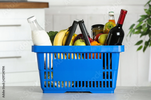 Shopping basket with grocery products on grey table indoors