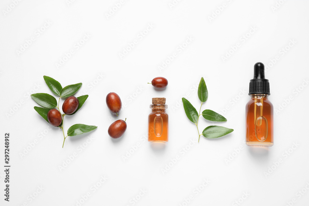 Glass bottles with jojoba oil and seeds on white background, top view Glass bottles with jojoba oil and seeds on white background, top view