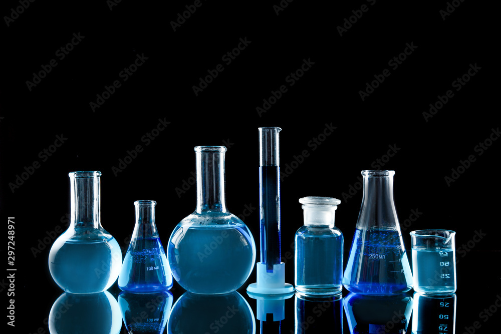 Laboratory glassware with blue liquids on black background Laboratory glassware with blue liquids on black background