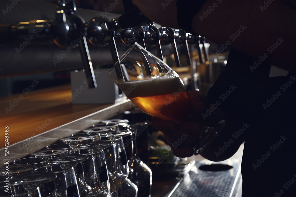 Bartender pouring beer into glass in pub, closeup Bartender pouring beer into glass in pub, closeup