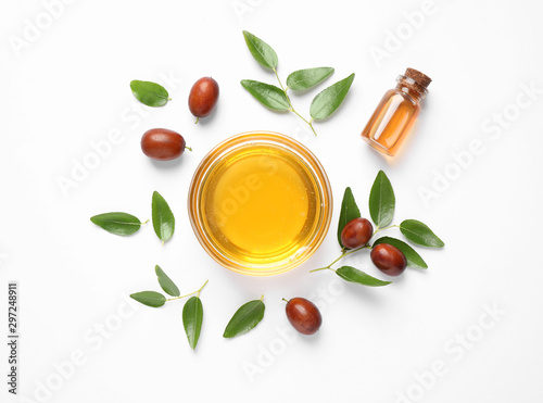 Bowl with jojoba oil and seeds on white background, top view photo