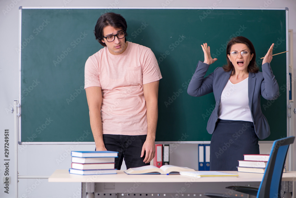 Old female teacher and male student in the classroom Old female teacher and male student in the classroom