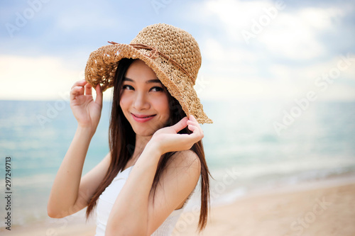 Beautiful girl young woman asia in a  hat smiling on the beach at sunset,enjoy summer vacation on the beach.