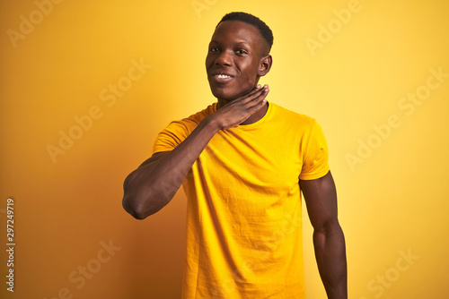 Young african american man wearing casual t-shirt standing over isolated yellow background cutting throat with hand as knife, threaten aggression with furious violence
