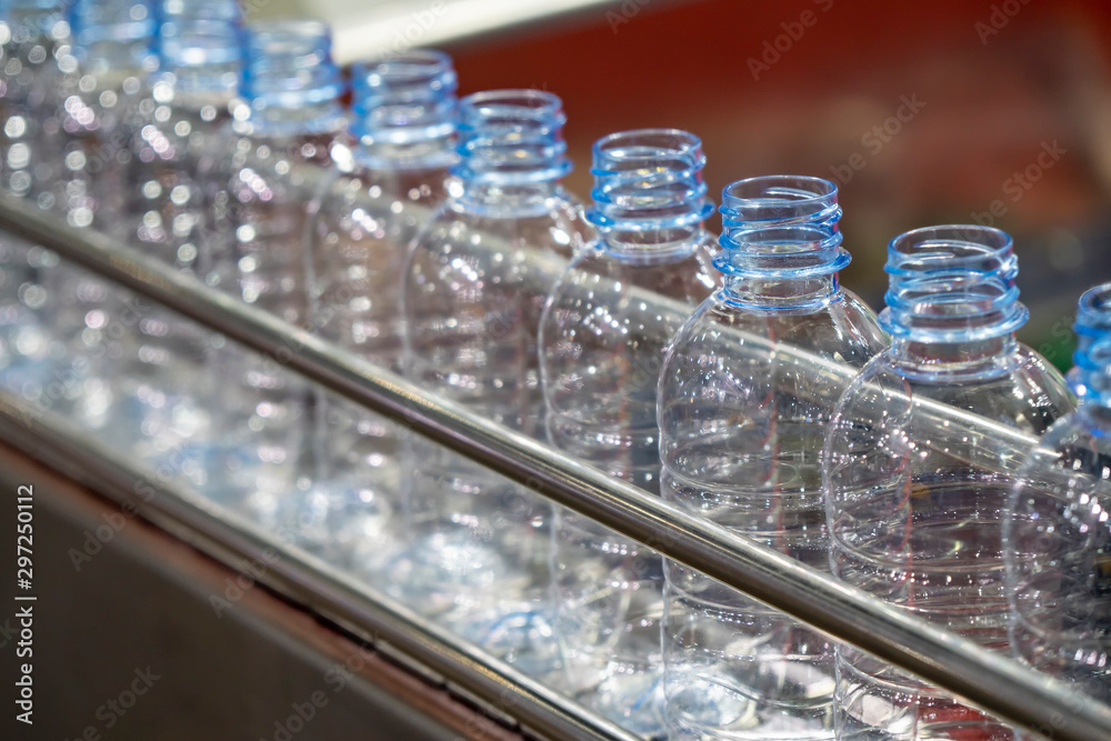 The PET bottles on the conveyor belt for filling process in the drinking water factory. The drinking water factory production process by automatic filling machine in the plant. The PET bottles on the conveyor belt for filling process in the drinking water factory. The drinking water factory production process by automatic filling machine in the plant.