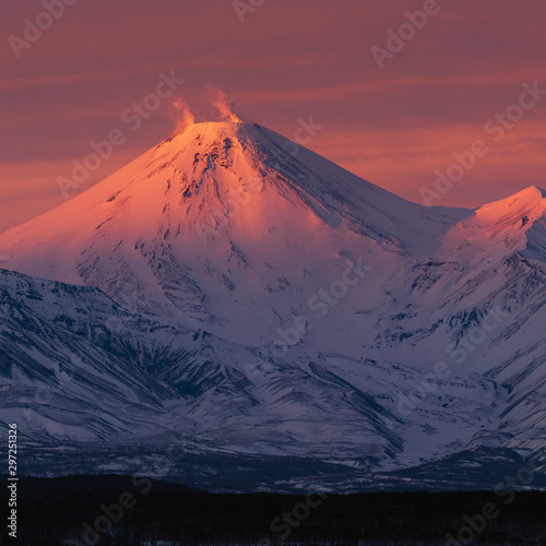 Winter volcanic landscape of Kamchatka Peninsula at purple-violet sunset: active Avacha Volcano erupting gas, ash - popular attraction, travel destinations. Eurasia, Russian Far East, Kamchatka Region
