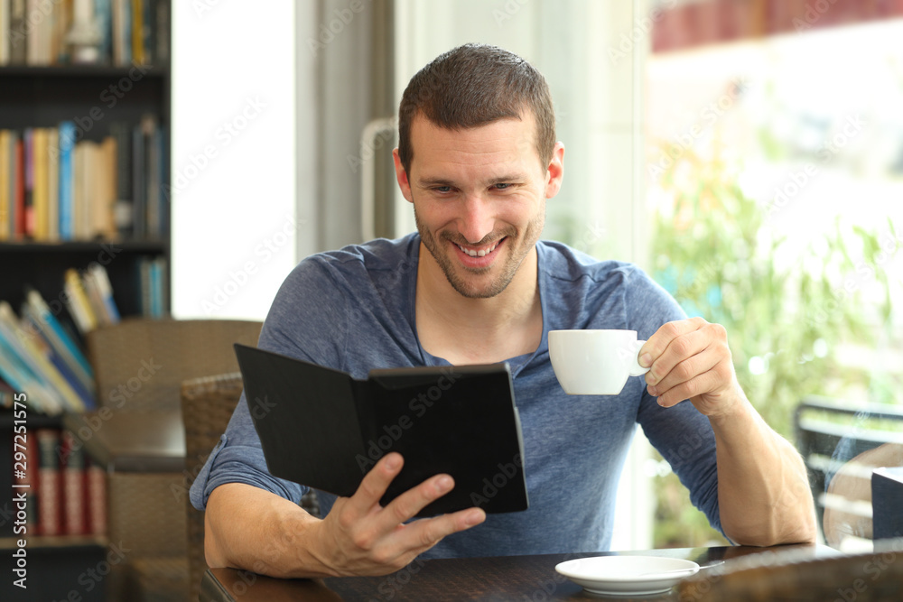 Happy man reading an ebook in a coffee shop Happy man reading an ebook in a coffee shop