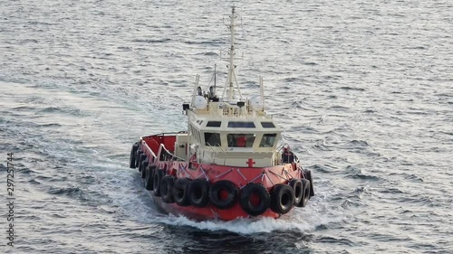 Dutch harbor port Skagen tugboat with tire protected boat sides sails to large tanker Onyx in rippling sea close view