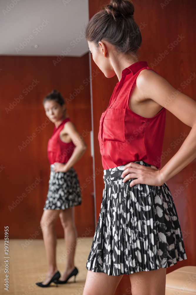 Woman looking in mirror happy of weight loss body image. Asian girl trying  on clothes choosing