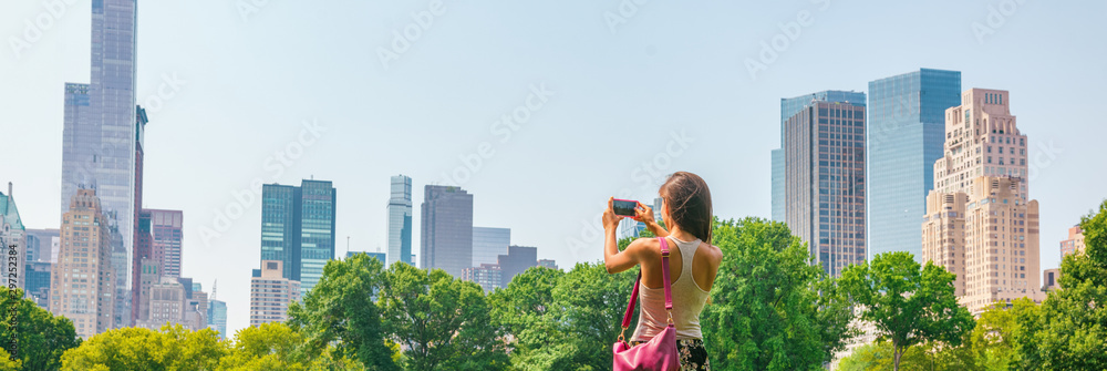 New York City tourist taking photo with phone of NYC Skyline of skyscrapers buildings towers in summer travel vacation panoramic banner background. - obrazy, fototapety, plakaty 