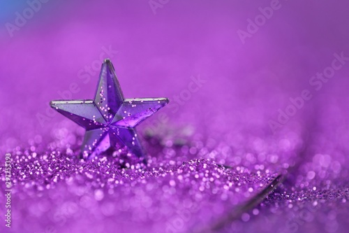 Christmas background.Violet star close-up on a lilac glitter background on a blurry purple background.