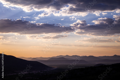 Panorama au couché du soleil de montagnes et ciel orange avec nuages gris