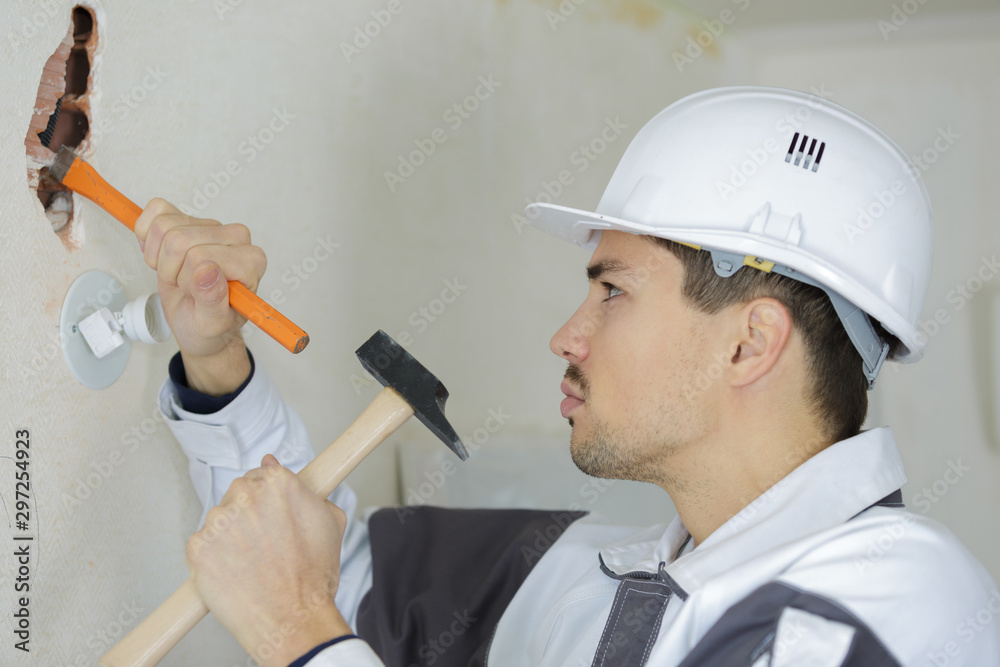 the photo depicts a man with a chisel and hammer