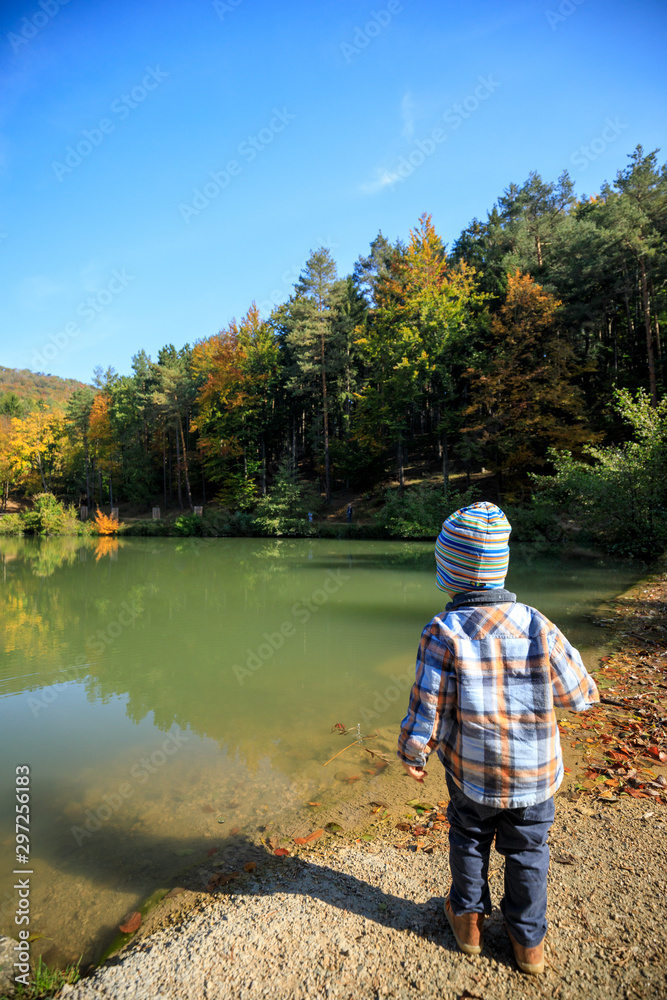 child at a autumn lake with a beautiful forest child at a autumn lake with a beautiful forest
