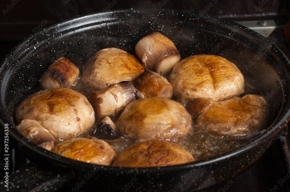 Roasting mushrooms in a black frying pan.Healthy food Roasting mushrooms in a black frying pan.Healthy food