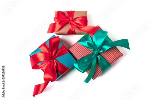 Three natural paper wrapped gift boxes with atlas ribbon bows of traditional colours, isolated on white