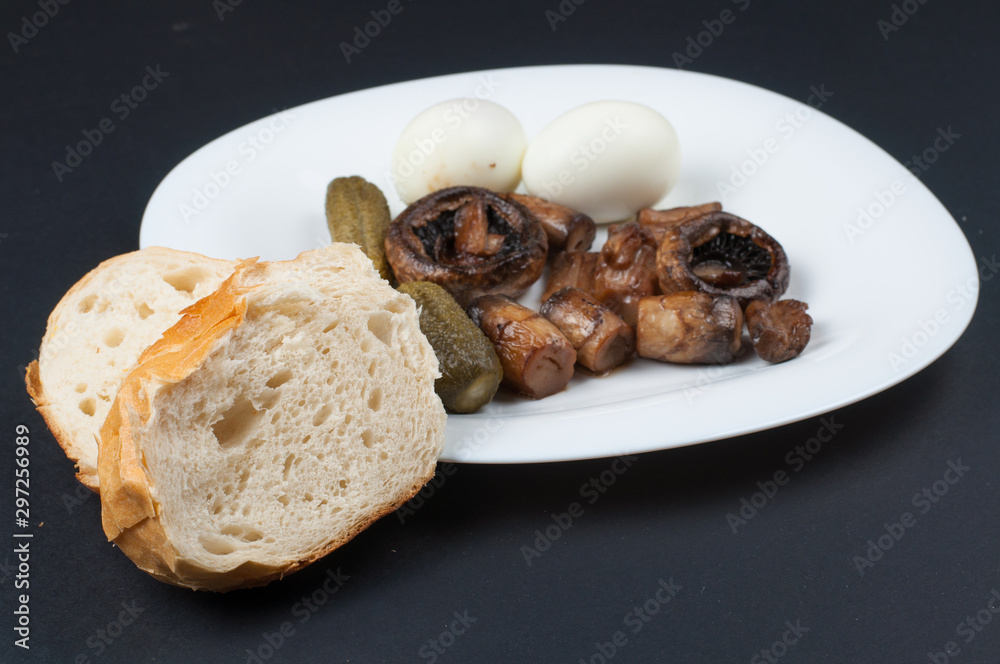 Mushrooms and boiled eggs on a white plate isolated on a black background.Natural food