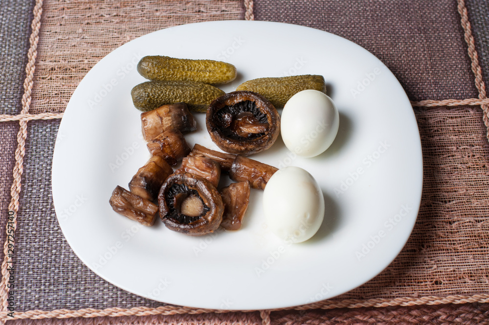 Mushrooms,boiled eggs and cucumber in a white plate on table Mushrooms,boiled eggs and cucumber in a white plate on table