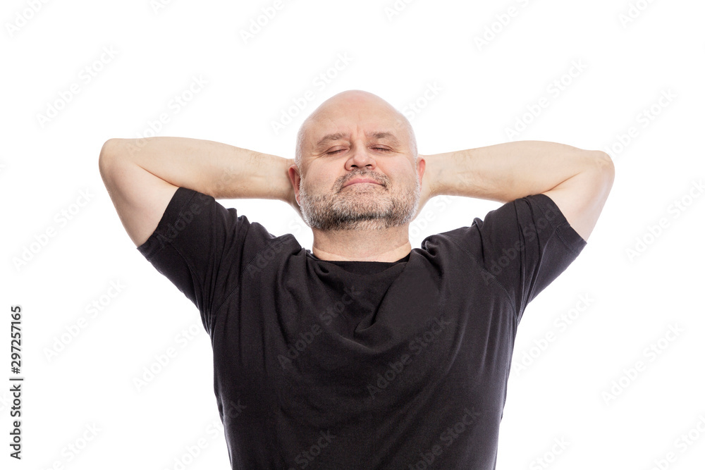 Bald middle-aged man in a black T-shirt, hands behind his head, smiling. Isolated over white background. Bald middle-aged man in a black T-shirt, hands behind his head, smiling. Isolated over white background.