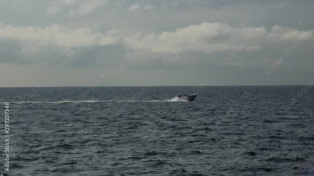 small motorboat sails fast and crosses boundless Danish Straits water surface under grey sky and thick clouds small motorboat sails fast and crosses boundless Danish Straits water surface under grey sky and thick clouds