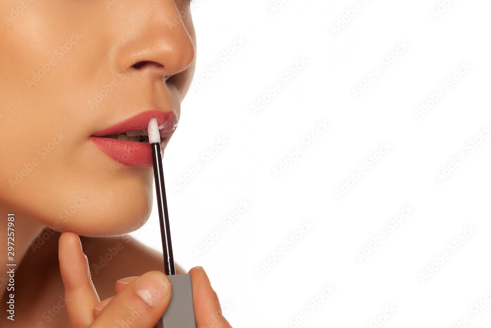 closeup of  woman applying lipgloss on white background