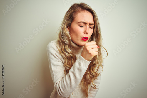 Beautiful woman wearing winter turtleneck sweater over isolated white background feeling unwell and coughing as symptom for cold or bronchitis. Healthcare concept.