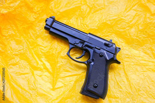 Gun lying on the yellow background. Legalising of weapon. Crime concept. photo
